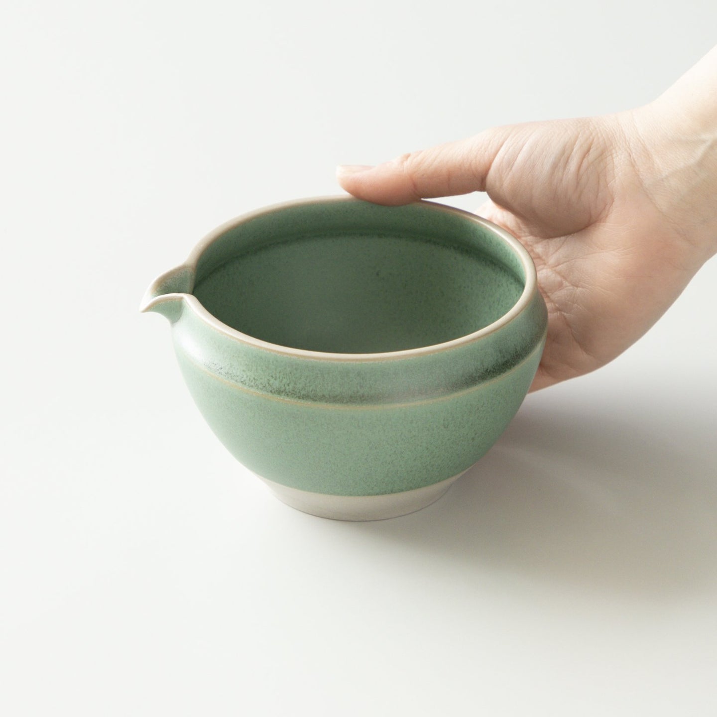 A hand holding the original ORIGAMI Katakuchi matcha bowl in Matsukaze Green